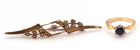 A gemset ring and a brooch: the ring set with a round sapphire with diamond highlights, with a plain