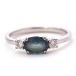 A 9ct sapphire and diamond ring, the oval blue-green sapphire set to either side with a round