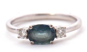 A 9ct sapphire and diamond ring, the oval blue-green sapphire set to either side with a round