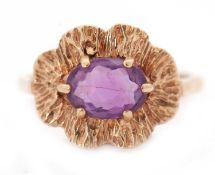 A 9ct amethyst ring, the oval amethyst with textured undulating surround, with plain band hallmarked