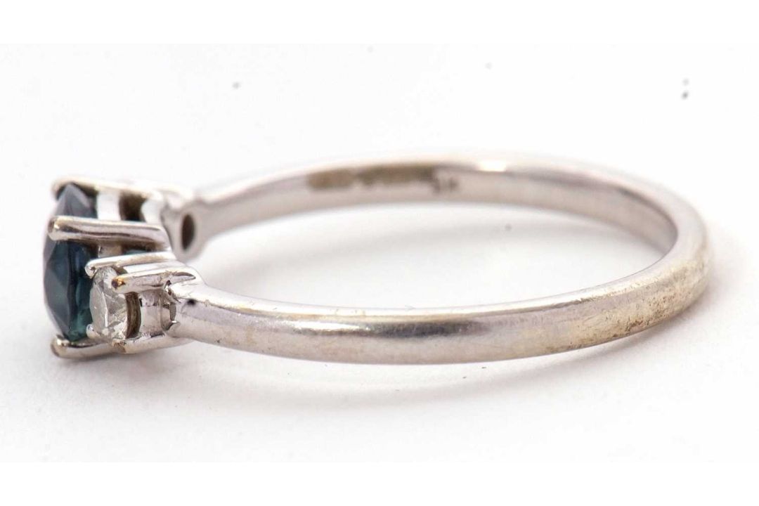A 9ct sapphire and diamond ring, the oval blue-green sapphire set to either side with a round - Image 6 of 8
