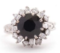 A sapphire and diamond ring, the central round deep blue sapphire surrounded by round and marquise