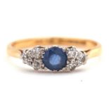A 22ct sapphire and diamond ring, the central round sapphire set to either side with round mixed cut