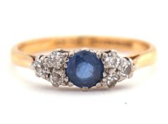 A 22ct sapphire and diamond ring, the central round sapphire set to either side with round mixed cut