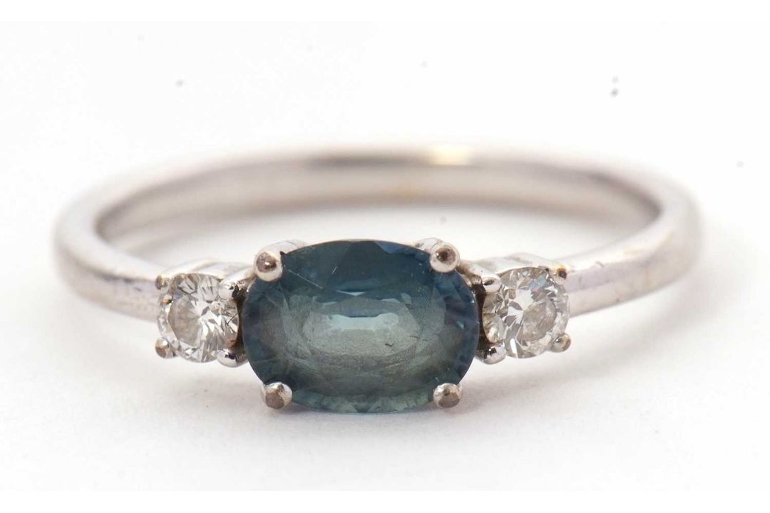 A 9ct sapphire and diamond ring, the oval blue-green sapphire set to either side with a round - Image 7 of 8