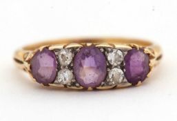 An amethyst and diamond ring, set with three graduated oval amethysts interspaced with single cut