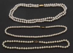 Three cultured pearl necklaces with gold clasps, to include a two strand necklace with clasp stamped