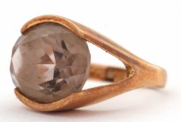 A 9ct smokey quartz ring, the oval smokey quartz in a horizontal tension settting, with split