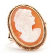 A cameo ring, the oval shell cameo, in collet mount with split shoulders and plain band of