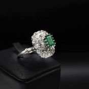 A WHITE METAL EMERALD AND DIAMOND RING.