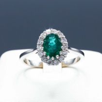 AN 18CT WHITE GOLD EMERALD AND DIAMOND CLUSTER RING.