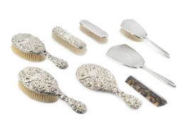 An Edwardian silver backed four piece dressing table set, embossed with scrolling foliage, by Nathan