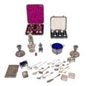 A collection of silver, to include a cigarette case, a pair of loaded candlesticks, a blue glass-