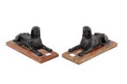 Two black resin Sphinx figures mounted on rectangular marble plinths.