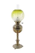 A Victorian brass oil lamp with a green glass shade.