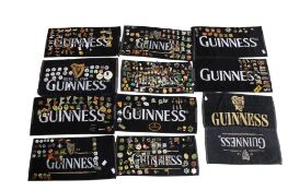 A collection of assorted Guinness enamel and other badges on several advertising beer bar towels