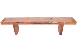 A substantial contemporary hardwood bench. Raised on rectangular supports.
