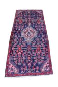 A red, pink and blue handmade wool narrow rug.