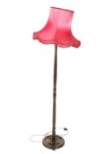 A vintage oak standard lamp. Raised on a circular base with a red fringe shade.