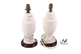 A pair of creamware ceramic table lamps. Raised on a turned wooden base.