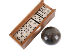 A 19th century glass paperweight and a box set of dominoes.