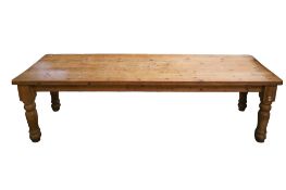 A large farmhouse style pine kitchen table. Raised on baluster supports.