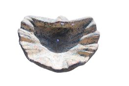 A vintage terracotta garden feature shaped as a clam shell.