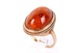 A 9ct gold and amber ring. The large cabochon of circa 1.8cm x 1.3cm, the shank hallmarked.
