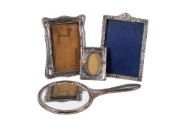 Three silver and white metal photograph frames and a silver hand mirror.