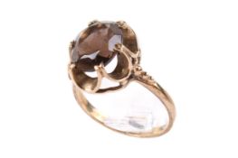 A 9ct gold smoky quartz dress ring. The oval cut stone circa 1.1cm x 0.