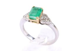 An 18ct gold emerald and diamond ring. The emerald cut central stone of circa 0.