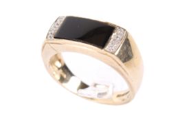 A 9ct gold and onyx ring. The slightly convex black panel circa 0.6cm x 1.