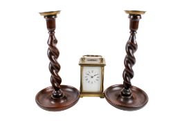 A pair of oak barley twist candlesticks and a French brass carriage clock.