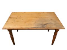 A pine kitchen table. Raised on turned tapering supports.