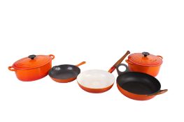 Five pieces of orange Le Creuset kitchenalia.