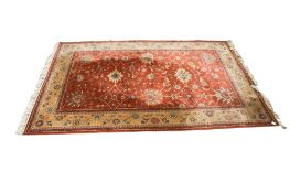 A large 20th century Chinese rug. Decorated with lotus flowers and scripture borders, in a coral.