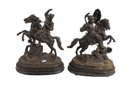A pair of cast metal figures of medieval knights on horseback.