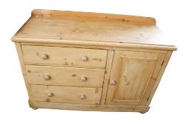 A stripped pine cabinet. With three drawers and one cupboard door, turned handles, on bun feet.