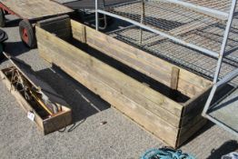 A large wooden garden planter trough