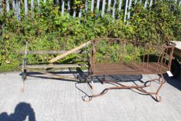 Two garden benches. To include an antique wrought iron strap work 'conversation' or 'love' bench,