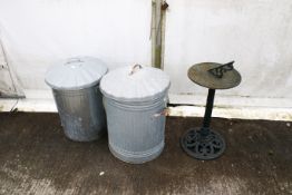 A green painted cast iron sun dial and two lidded galvanised bins. The sun dial raised on a column