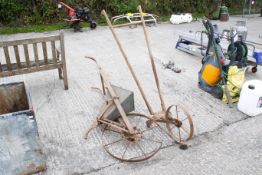 Two antique hand-pushed agricultural tools. To include a seed drill, and a cultivator. Both appear