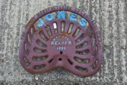 A vintage cast iron Jones Manual Reaper 1222 tractor seat. Painted red and blue. With 'The Plano