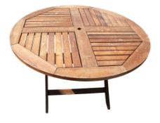 A circular teak folding garden table. With X-frame supports and umbrella hole. C120cm H73cm. All