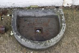 An antique carved stone trough or pump basin. Semi-circular form, with mounting or drainage hole.
