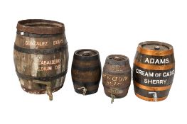 Five coopered oak barrels and a wicker-clad bottle. Some barrels with branding including Gonzalez