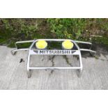 A Mitsubishi full front protection bar or bullbar. Chrome, with two mounted spotlights with yellow