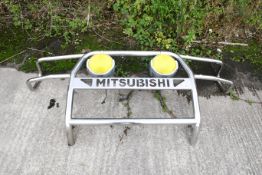 A Mitsubishi full front protection bar or bullbar. Chrome, with two mounted spotlights with yellow
