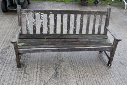 A Swan Seats teak garden bench. With armrests, horizontal seat base slats, and vertical backrest