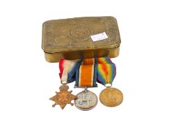 A trio of WWI medals on ribbons in a Princess Mary Christmas 1914 gift tin.